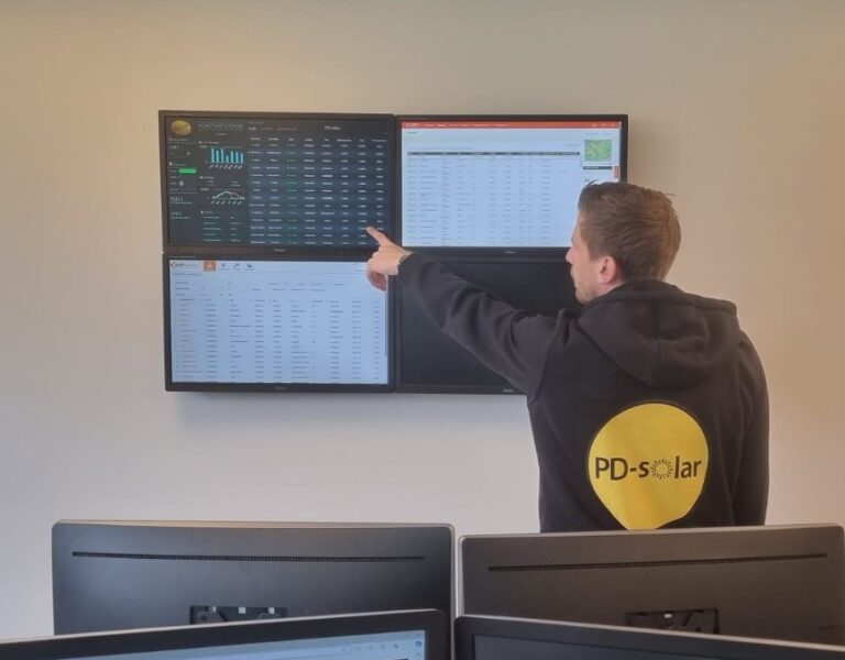 Medewerker van PD-Solar bekijkt monitoringgegevens op een groot scherm